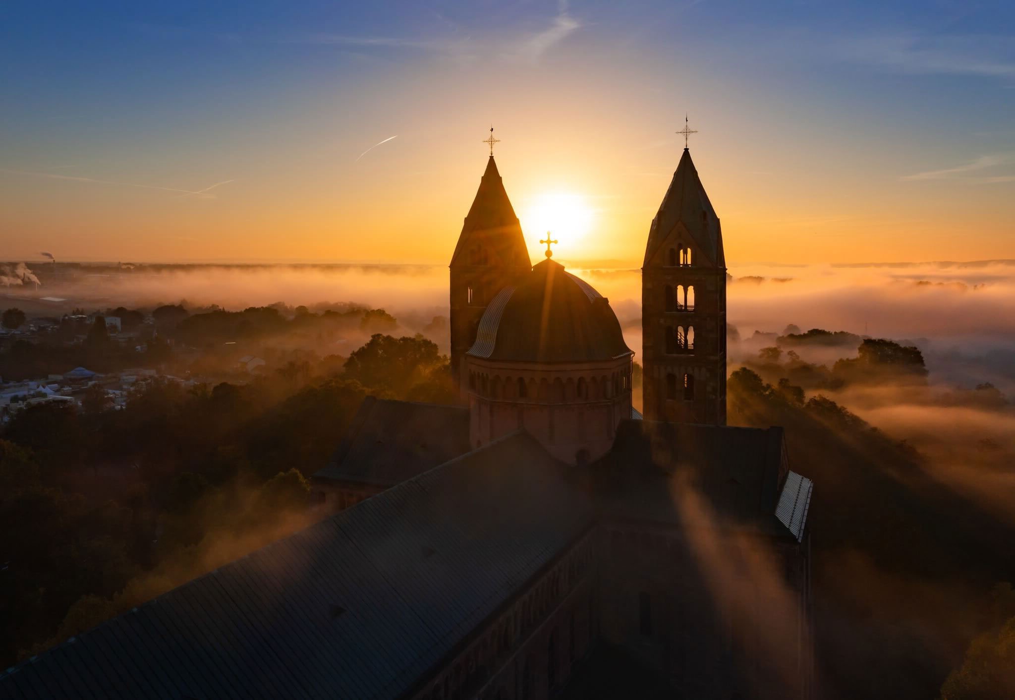 Kirchengebäude schaut bei Sonnenuntergang über den Wolken raus