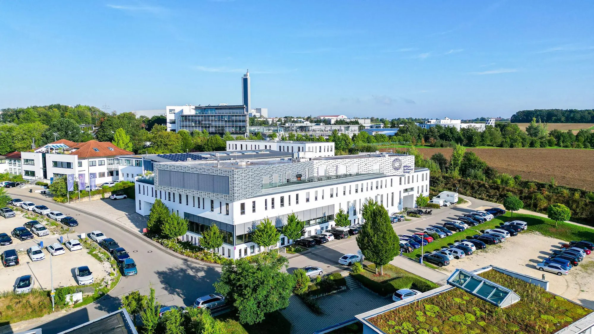 Eine Luftaufnahme des Hörvelsinger Wegs in Ulm. Dabei steht bei der Aufnahme das Firmengebäude der Wilken Software Group mit den umliegenden Parkplätzen im Vordergrund.