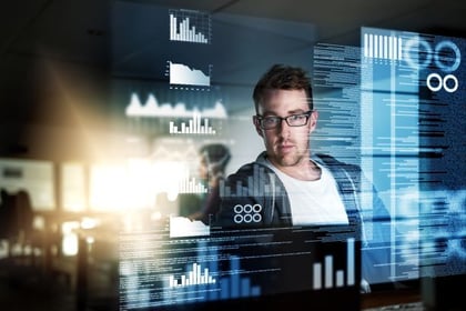 Ein Mitarbeiter blickt auf seinen Bildschirm, auf dem er Auswertungen und Statistiken sieht